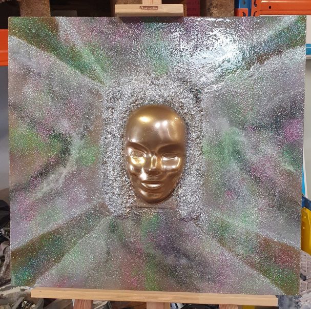 Visage doré intégré dans une texture colorée et abstraite.