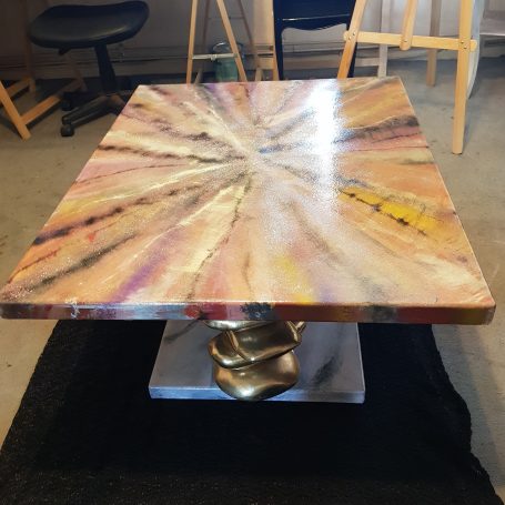 Table en résine époxy avec un motif coloré et un piètement en métal doré.