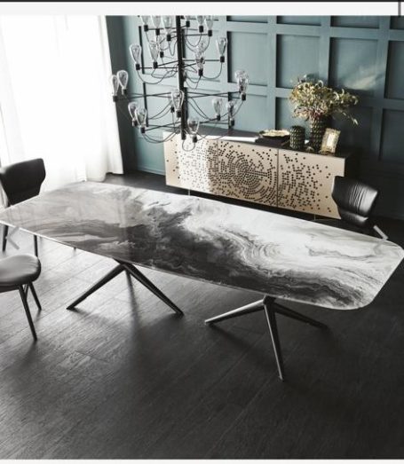 Table moderne avec un plateau marbré, entourée de chaises, dans un intérieur lumineux.